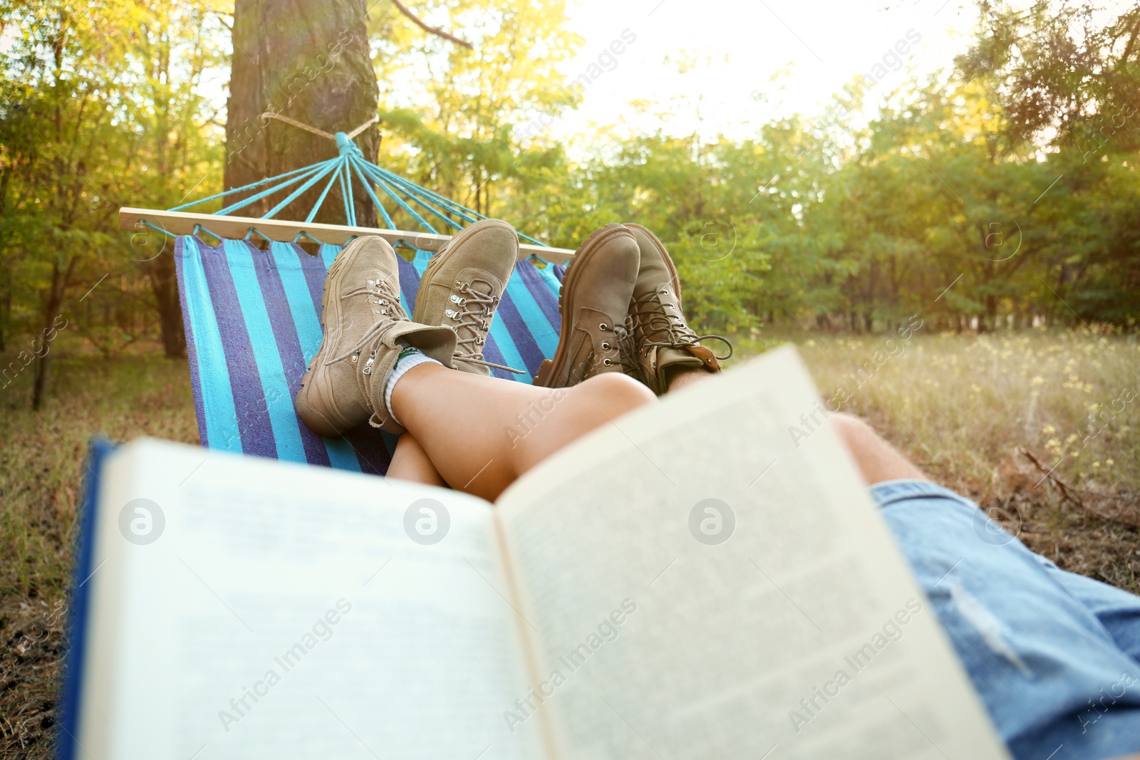 Photo of Lovely couple with book resting in comfortable hammock outdoors, closeup