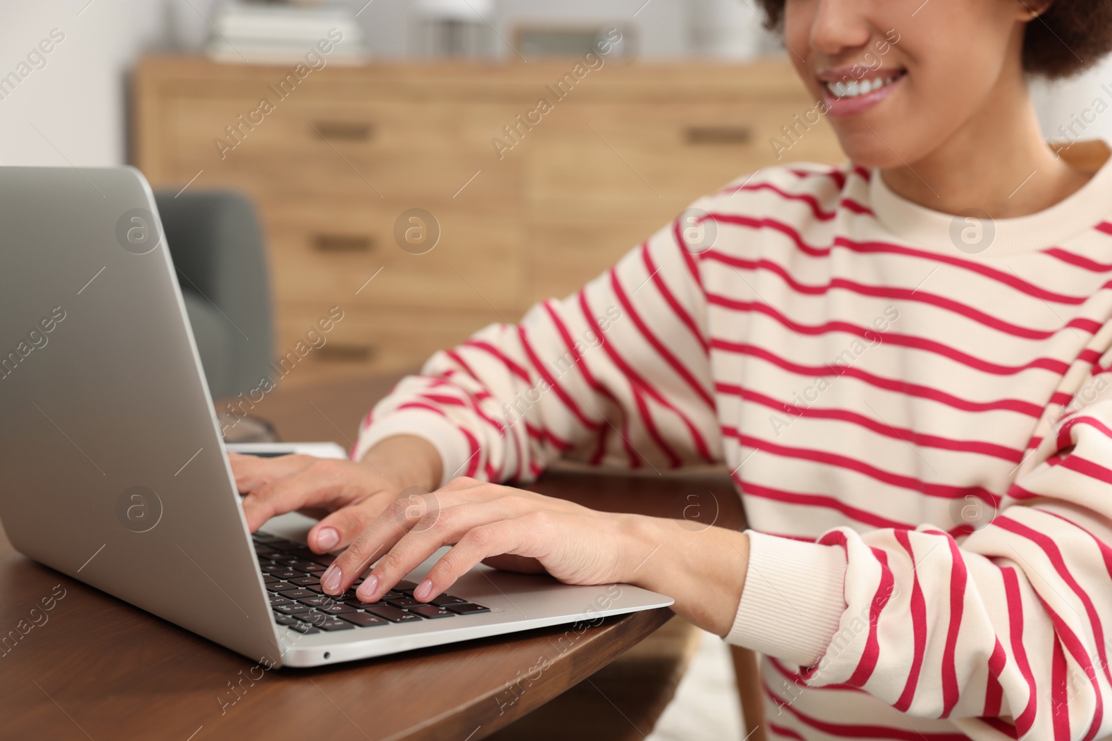 Photo of Woman using laptop at wooden coffee table in room, closeup