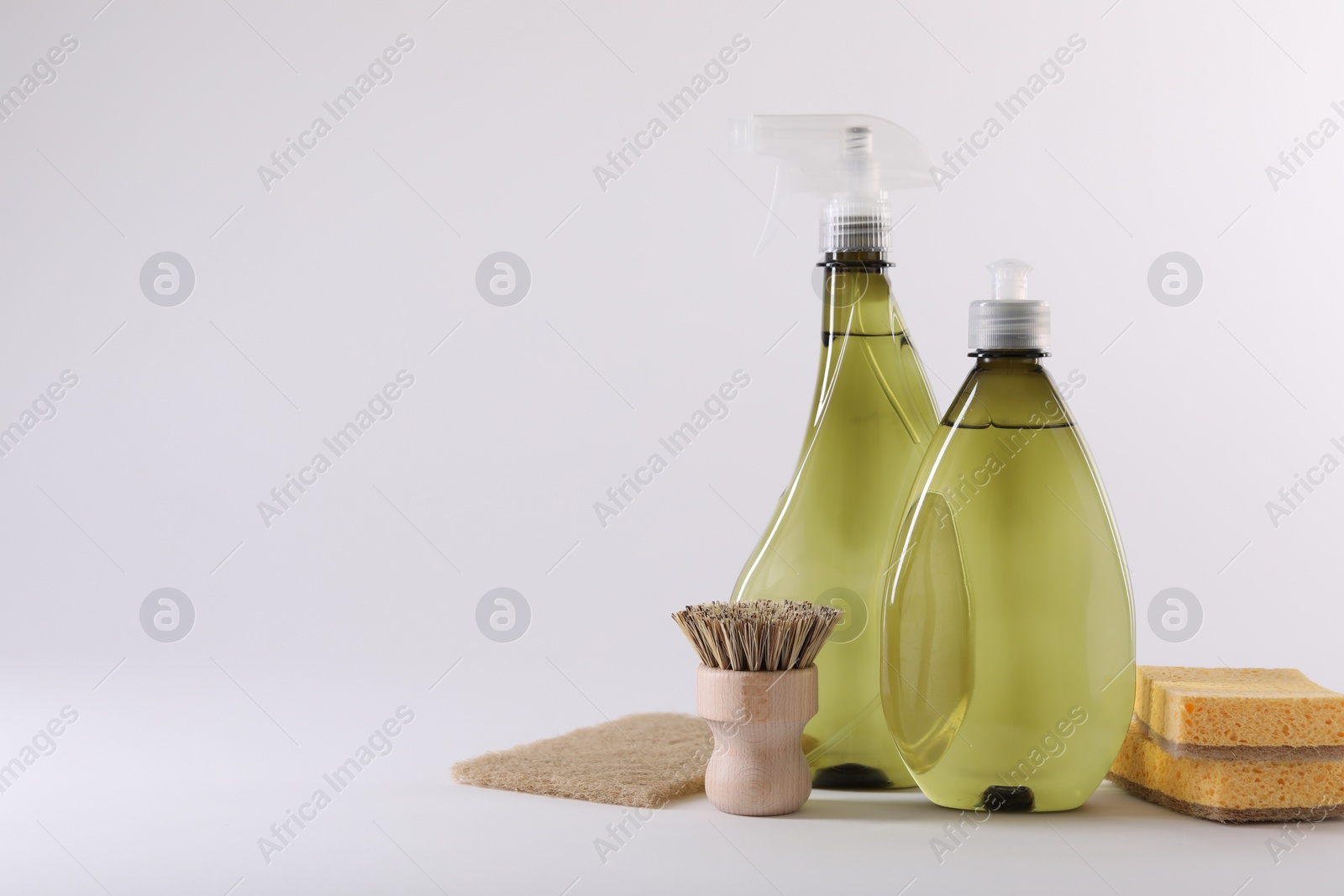 Photo of Bottles of cleaning product, brush and sponges isolated on white