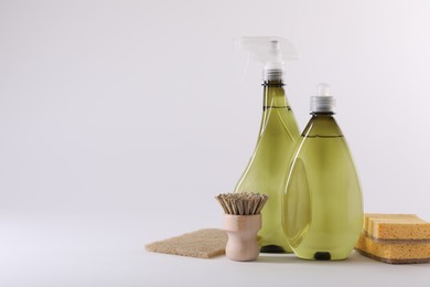 Photo of Bottles of cleaning product, brush and sponges isolated on white