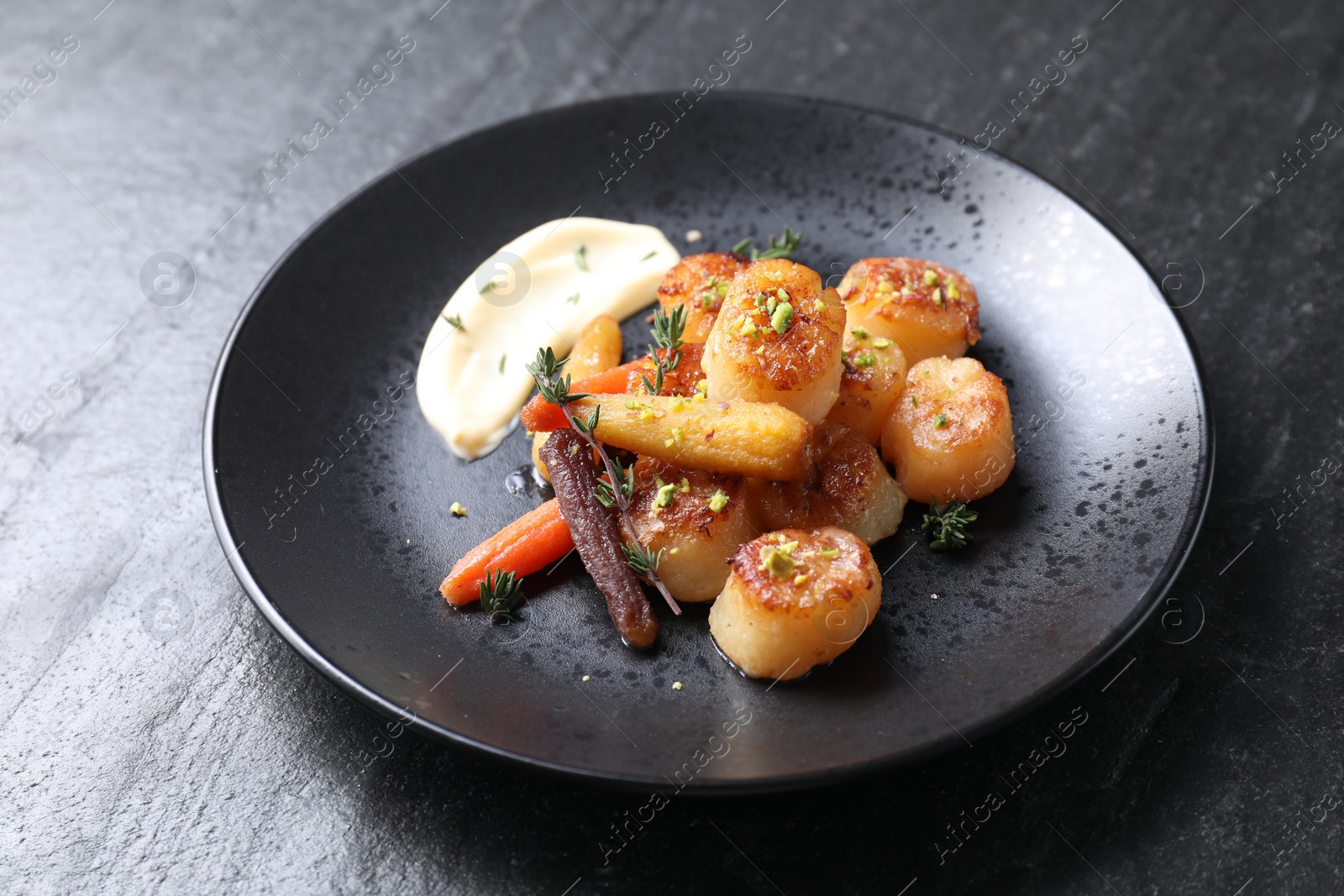 Photo of Delicious fried scallops on dark gray textured table, closeup