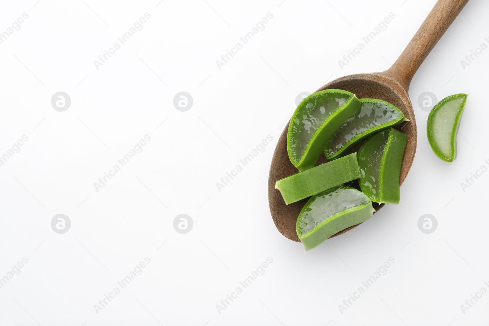 Photo of Wooden spoon with fresh aloe vera pieces on white background, top view. Space for text