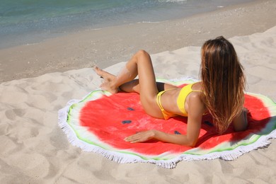 Woman with beach towel on sand near sea