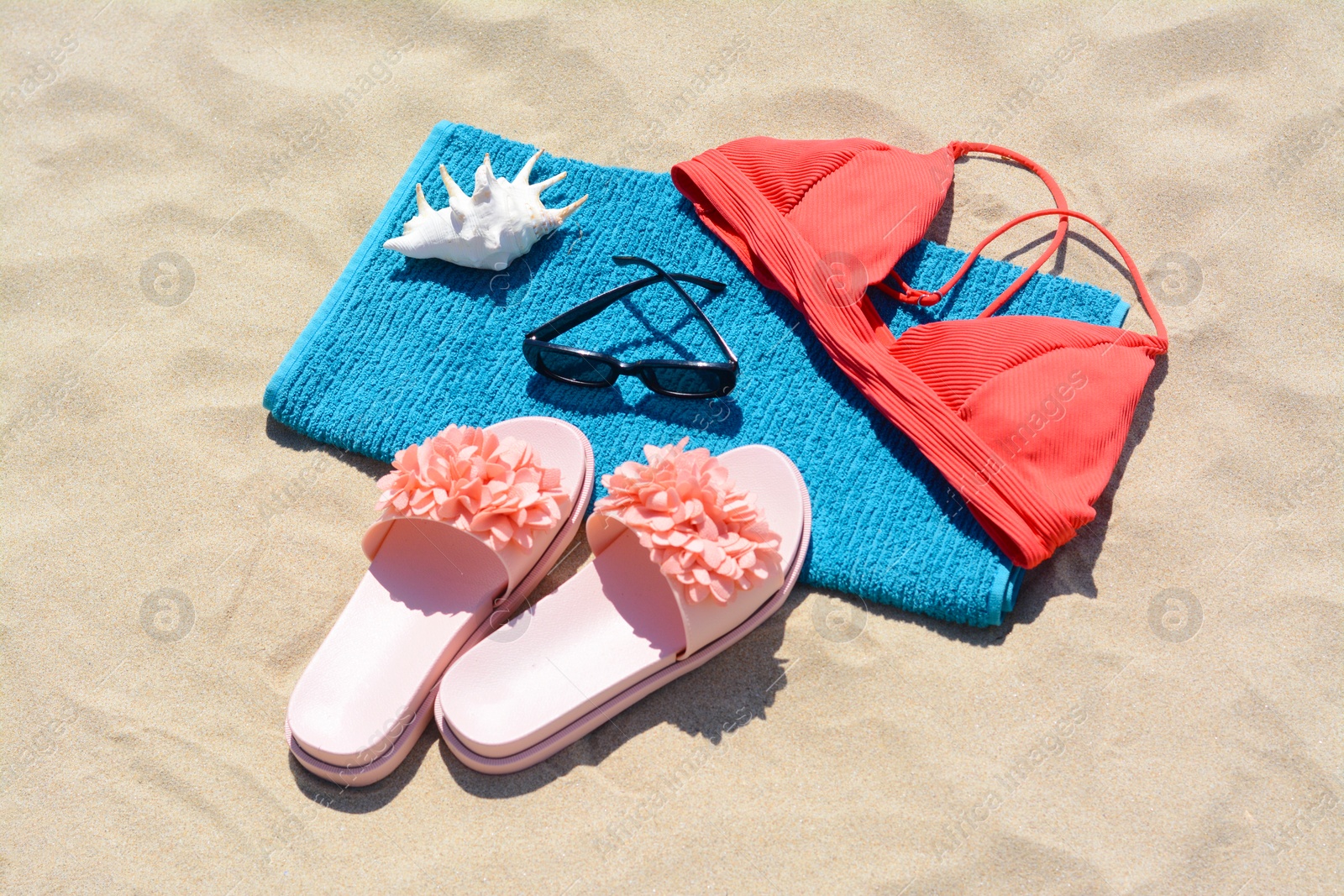 Photo of Towel, flip flops and bra on sand. Beach accessories