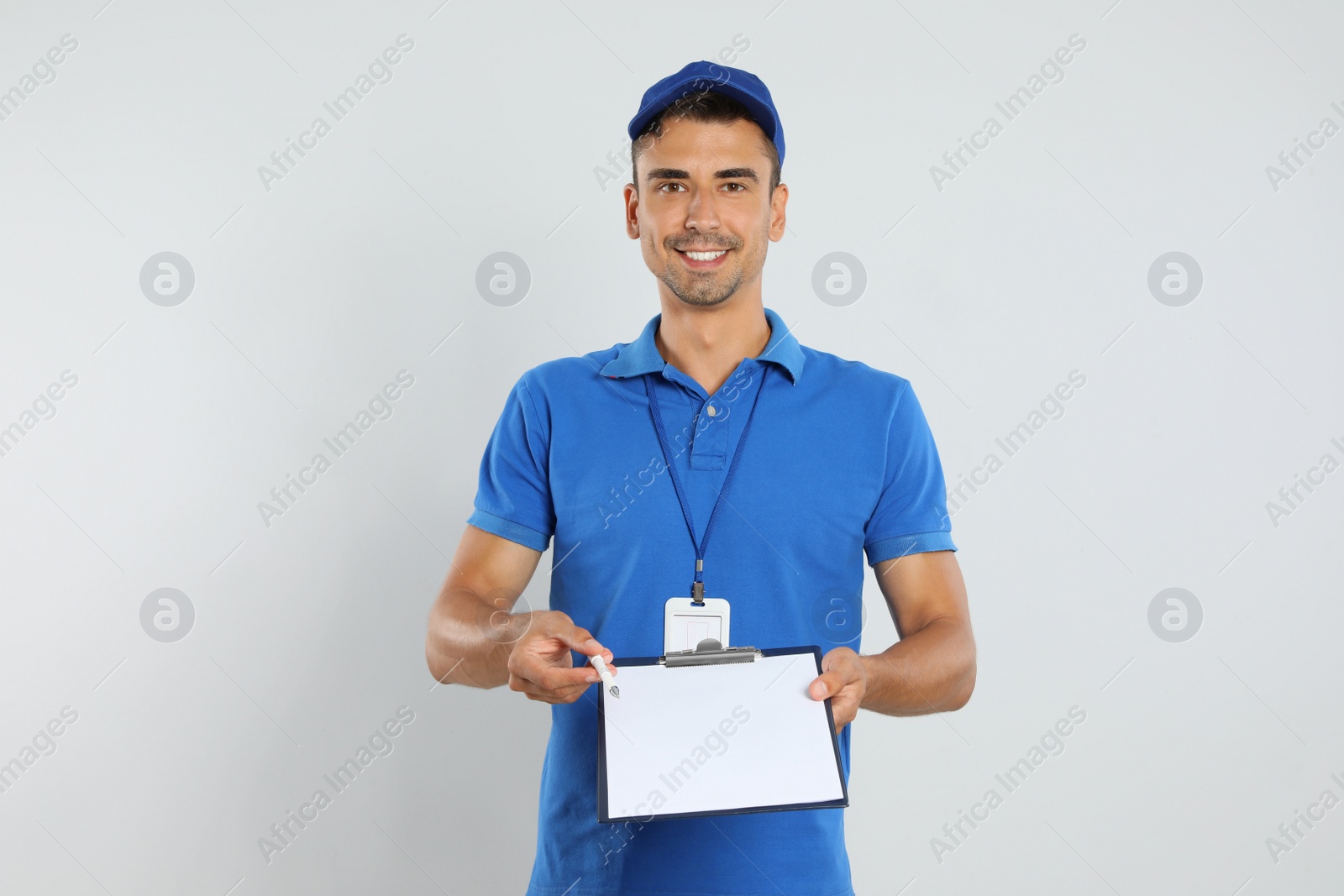 Photo of Happy young courier with clipboard on white background