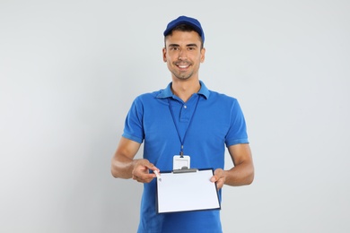 Happy young courier with clipboard on white background