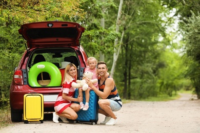 Photo of Happy family near car trunk with suitcases outdoors. Space for text