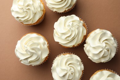 Tasty vanilla cupcakes with cream on dark beige background, top view