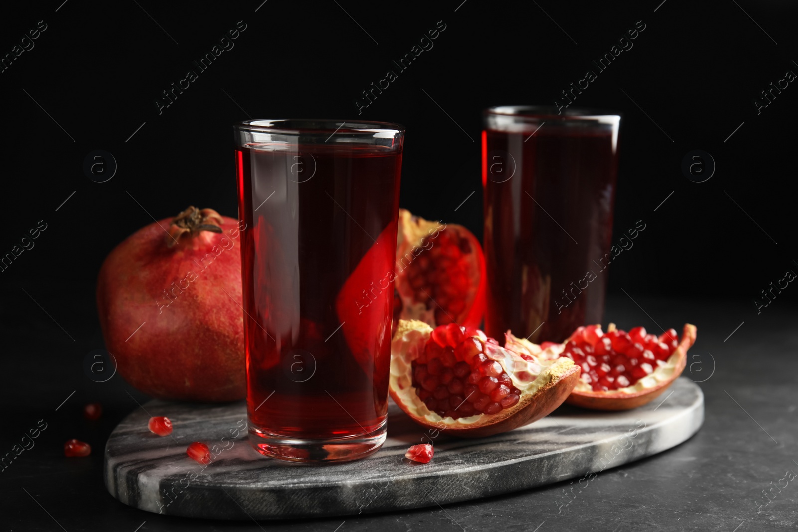 Photo of Pomegranate juice and fresh fruits on dark table