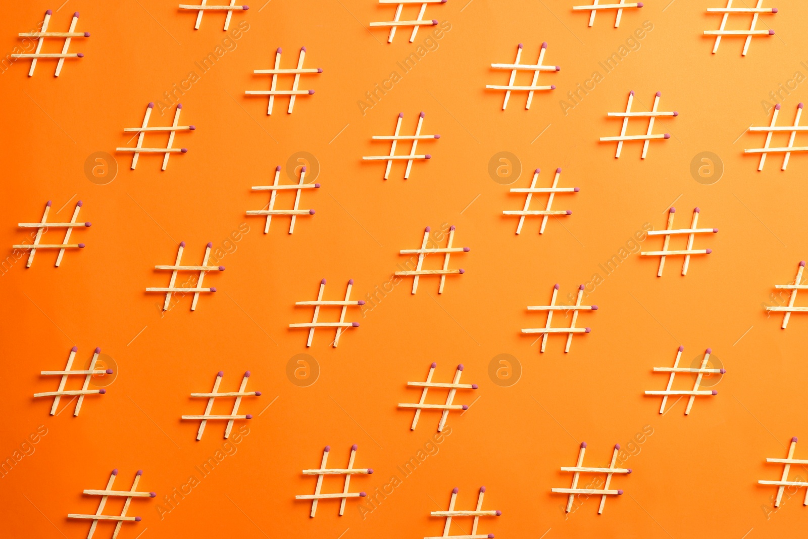 Photo of Hashtag symbols made of wooden matches on orange background, flat lay