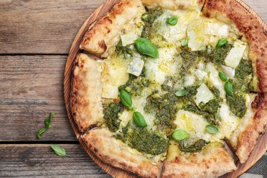 Delicious pizza with pesto, cheese and basil on wooden table, flat lay