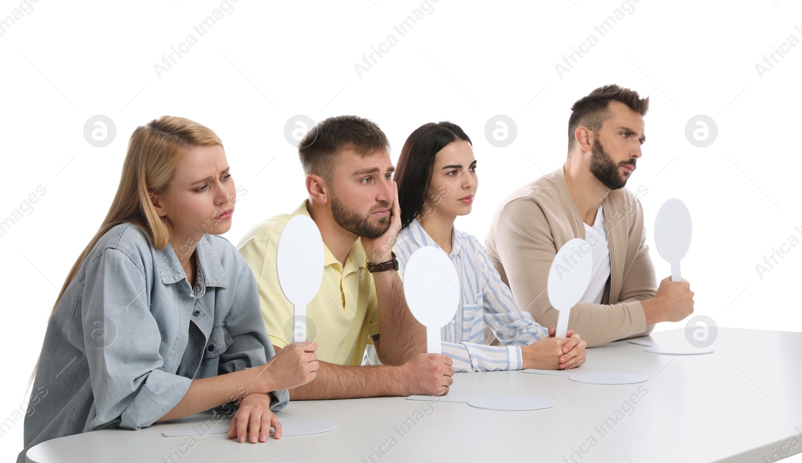 Photo of Panel of disappointed judges holding blank score signs at table on white background. Space for text