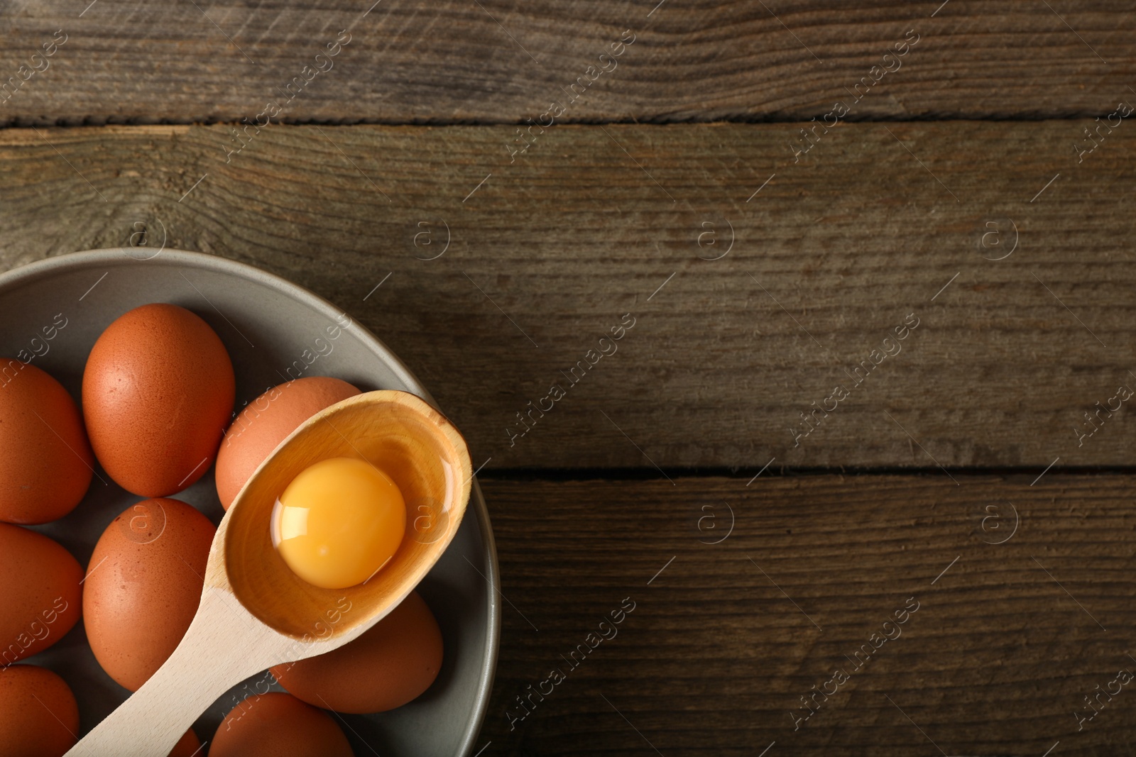 Photo of Raw chicken eggs on wooden table, top view. Space for text