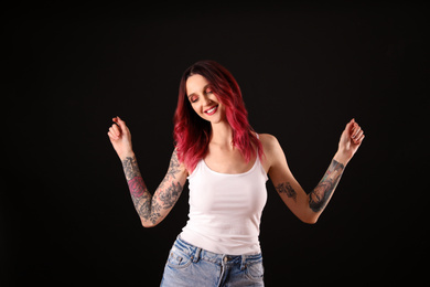 Photo of Beautiful woman with tattoos on arms against black background