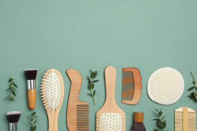 Flat lay composition with modern hair combs and brushes on green background. Space for text