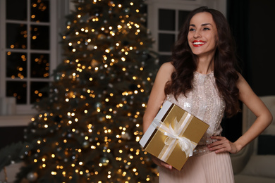 Photo of Beautiful woman with gift box in decorated room. Christmas celebration