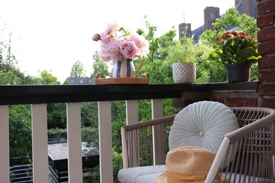 Different plants on railings and chair at cozy balcony outdoors