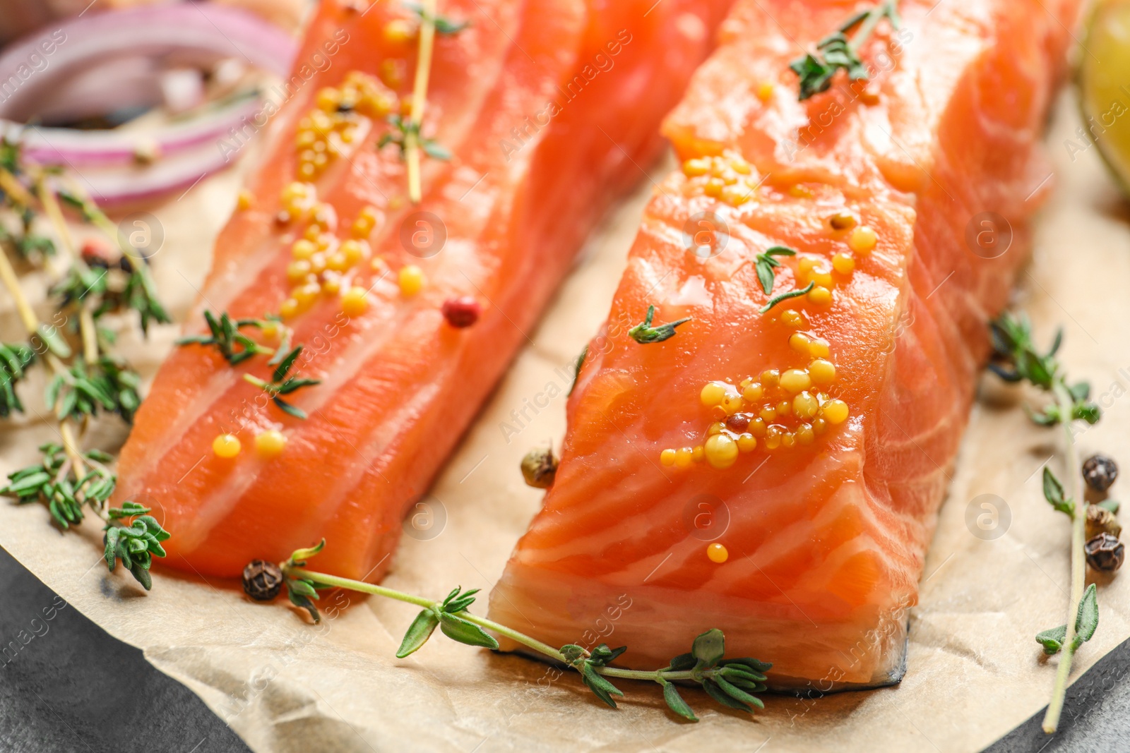 Photo of Fresh salmon with mustard and thyme on parchment, closeup