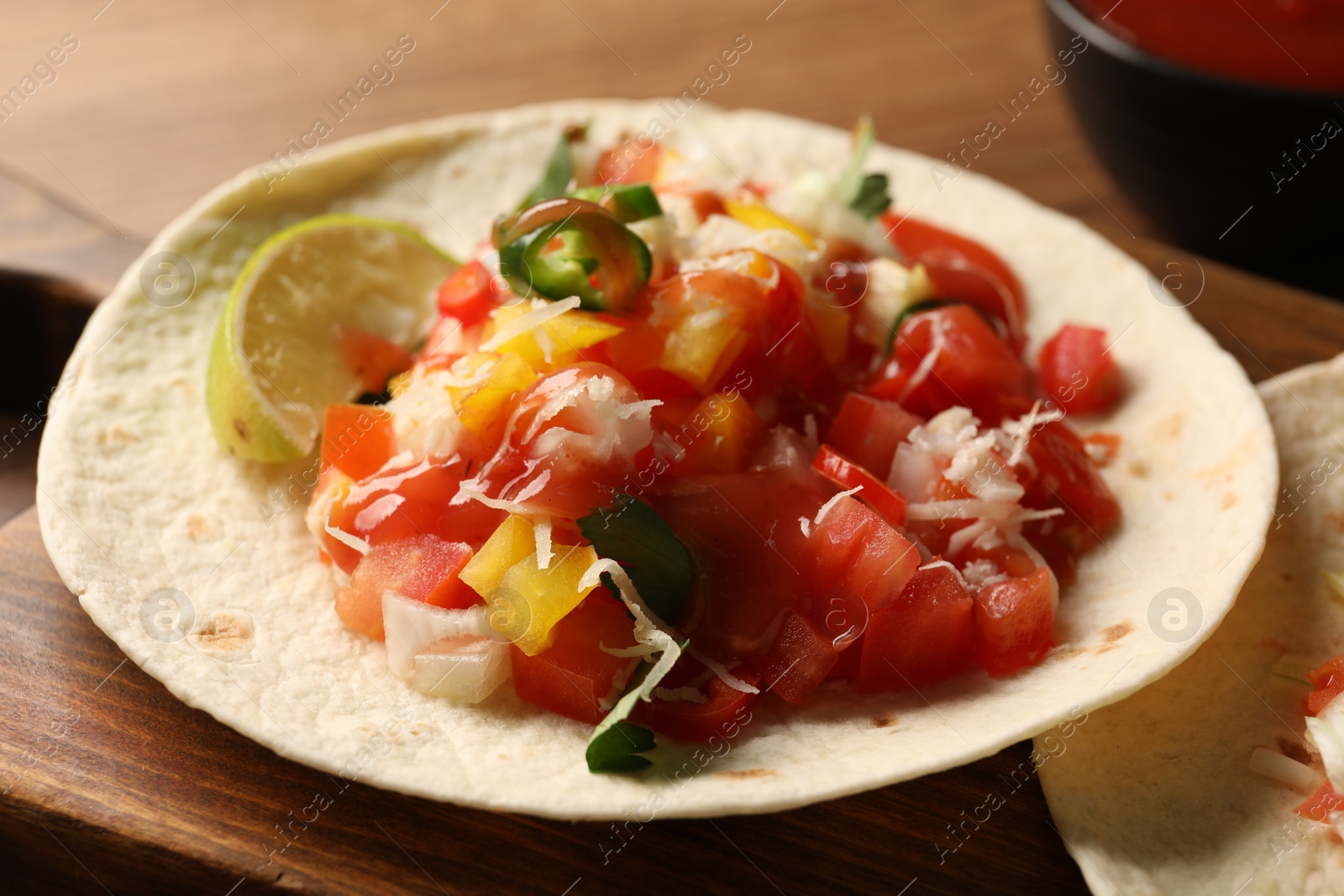 Photo of Delicious taco with vegetables, lime and ketchup on wooden table, closeup