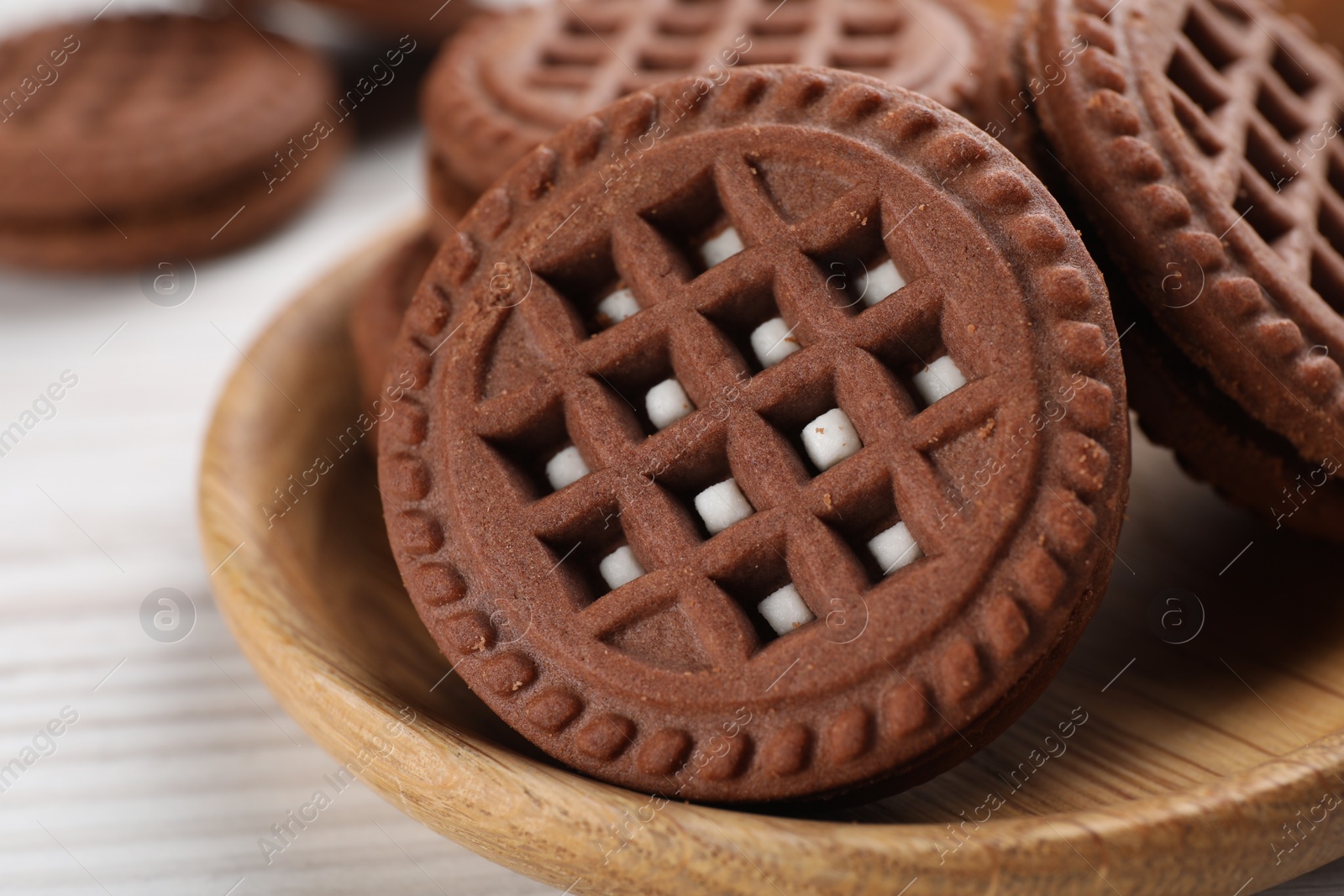 Photo of Tasty chocolate sandwich cookies with cream on white wooden table, closeup