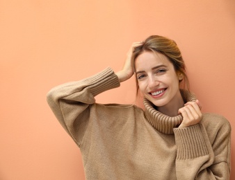 Photo of Beautiful young woman wearing knitted sweater on light brown background