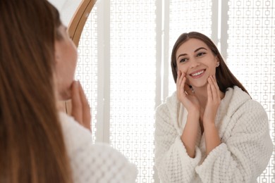 Photo of Young woman near mirror in bathroom. Skin care
