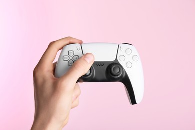 Photo of Man using wireless game controller on pink background, closeup