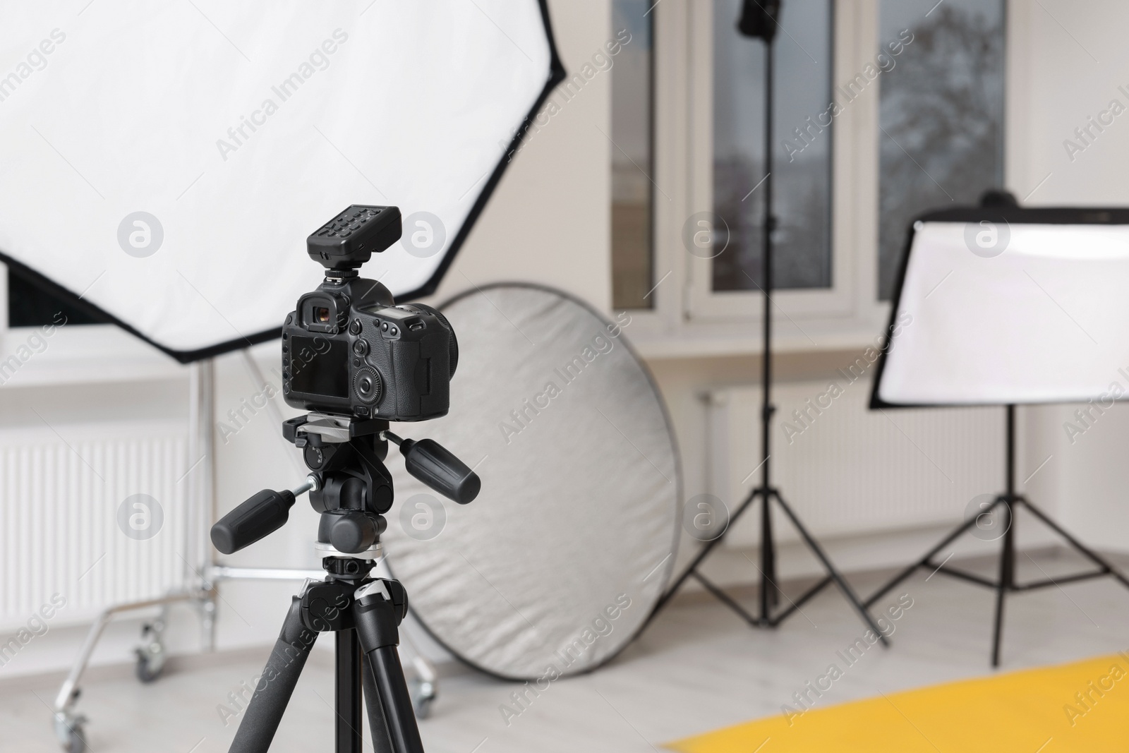 Photo of Camera on tripod and professional lighting equipment in modern photo studio, space for text