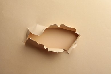 Photo of Hole in light beige paper on color background