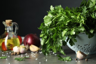 Photo of Fresh parsley, spices and other products on grey table, closeup