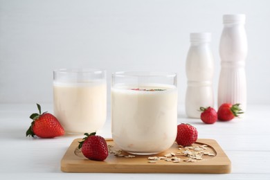 Photo of Tasty yogurt, oats and strawberries on white wooden table