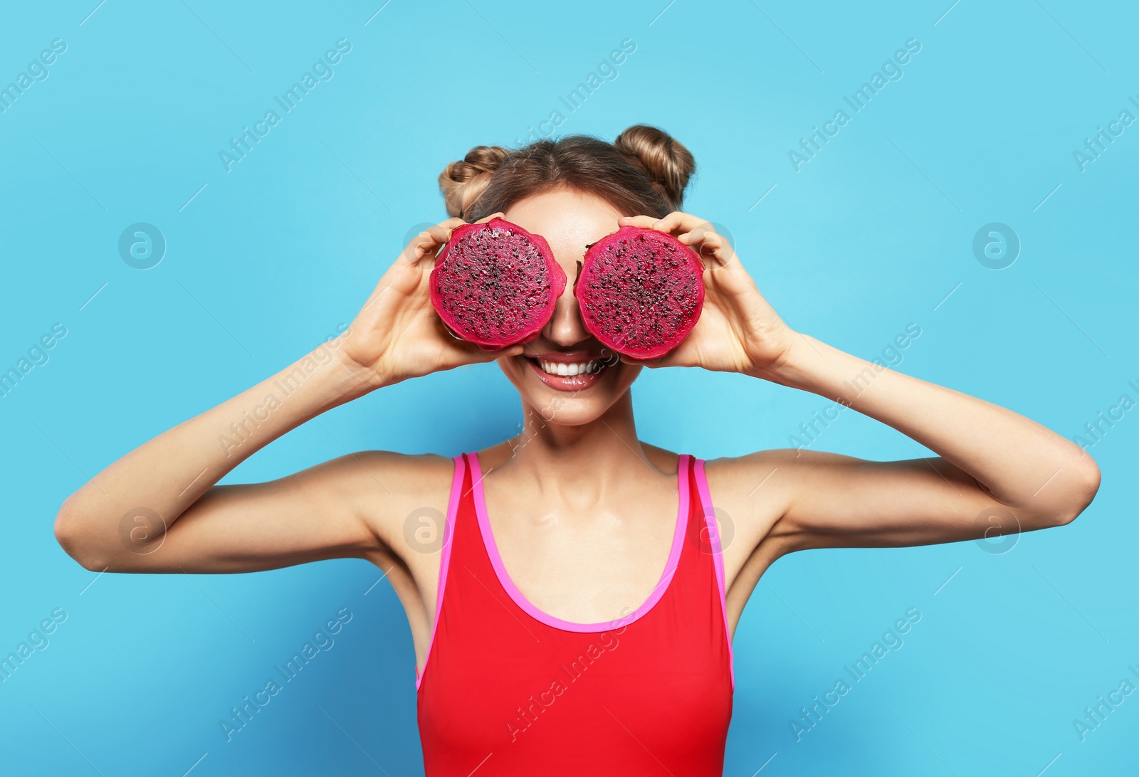 Photo of Young woman with fresh pitahaya on light blue background. Exotic fruit