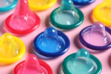 Colorful condoms on pink background, closeup view