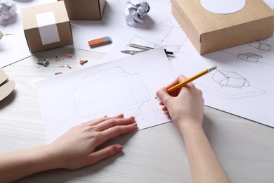 Photo of Woman creating packaging design at light wooden table, closeup