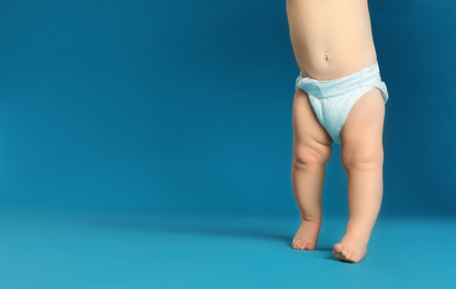 Cute little baby in diaper on light blue background, closeup. Space for text
