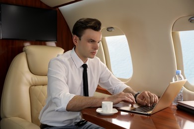Photo of Businessman working on laptop at table in airplane during flight