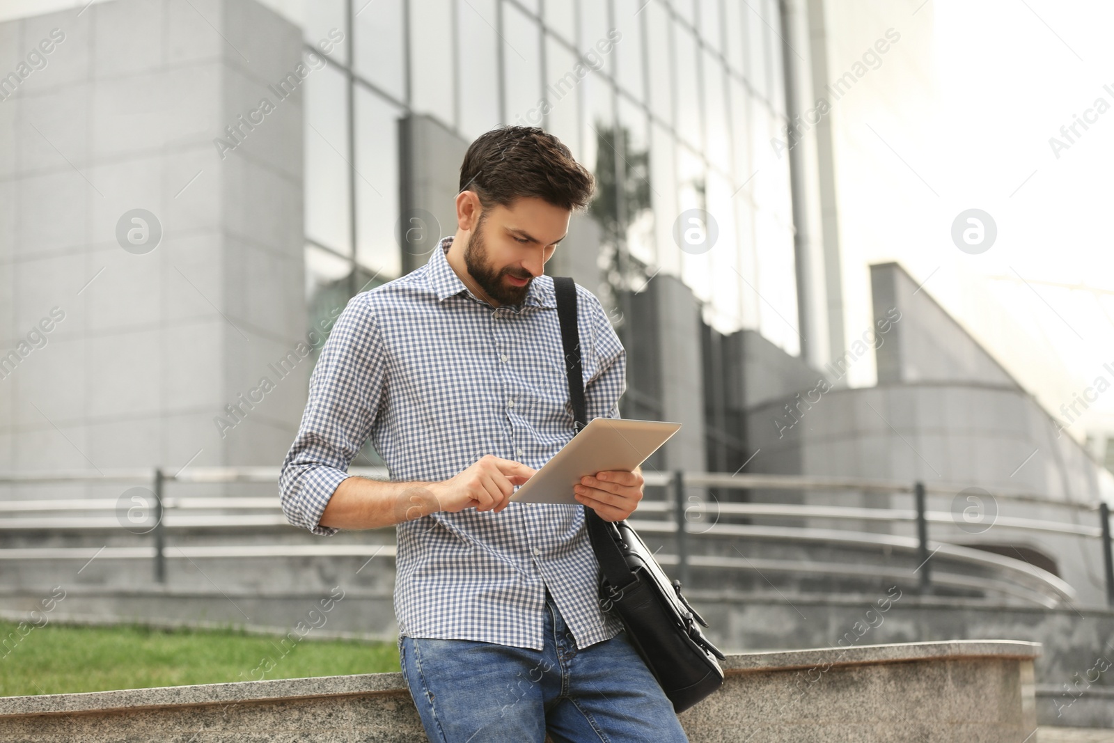 Photo of Handsome man working with tablet on city street