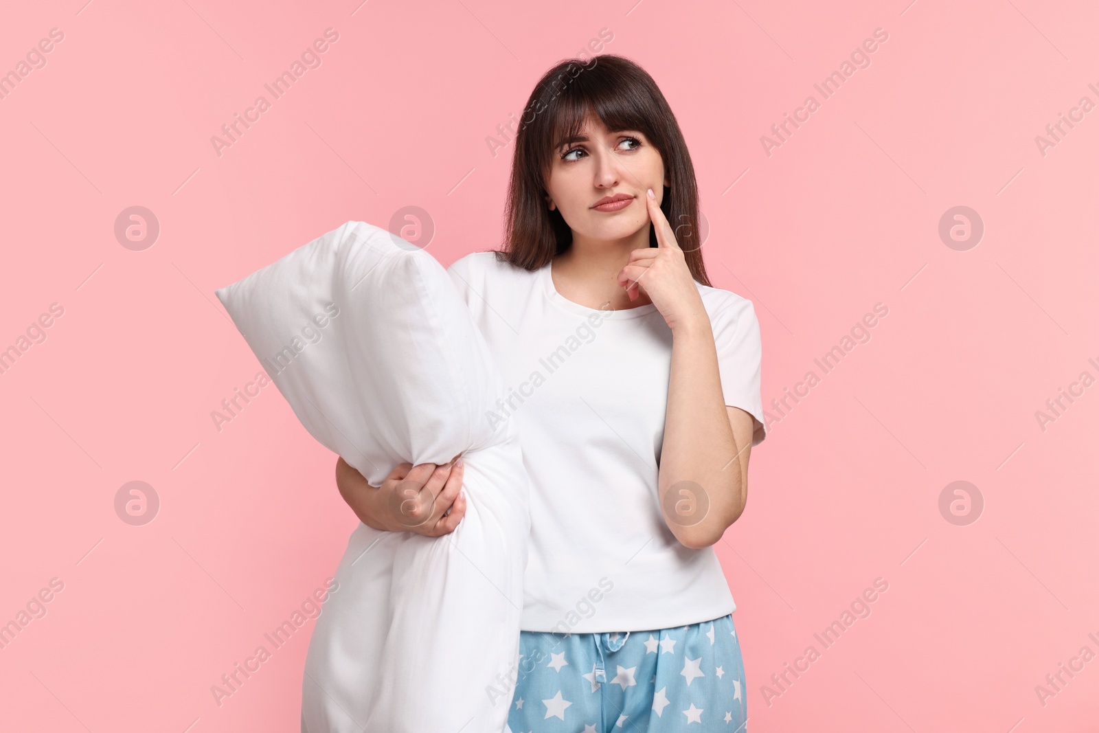 Photo of Woman in pyjama holding pillow on pink background