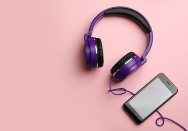 Photo of Stylish headphones and modern phone on color background, flat lay. Space for text