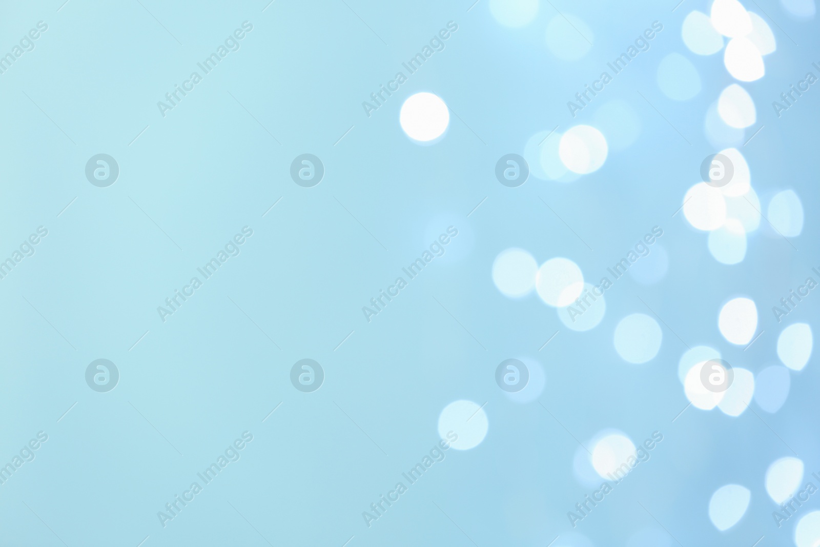Photo of Blurred view of beautiful lights on light blue background, space for text