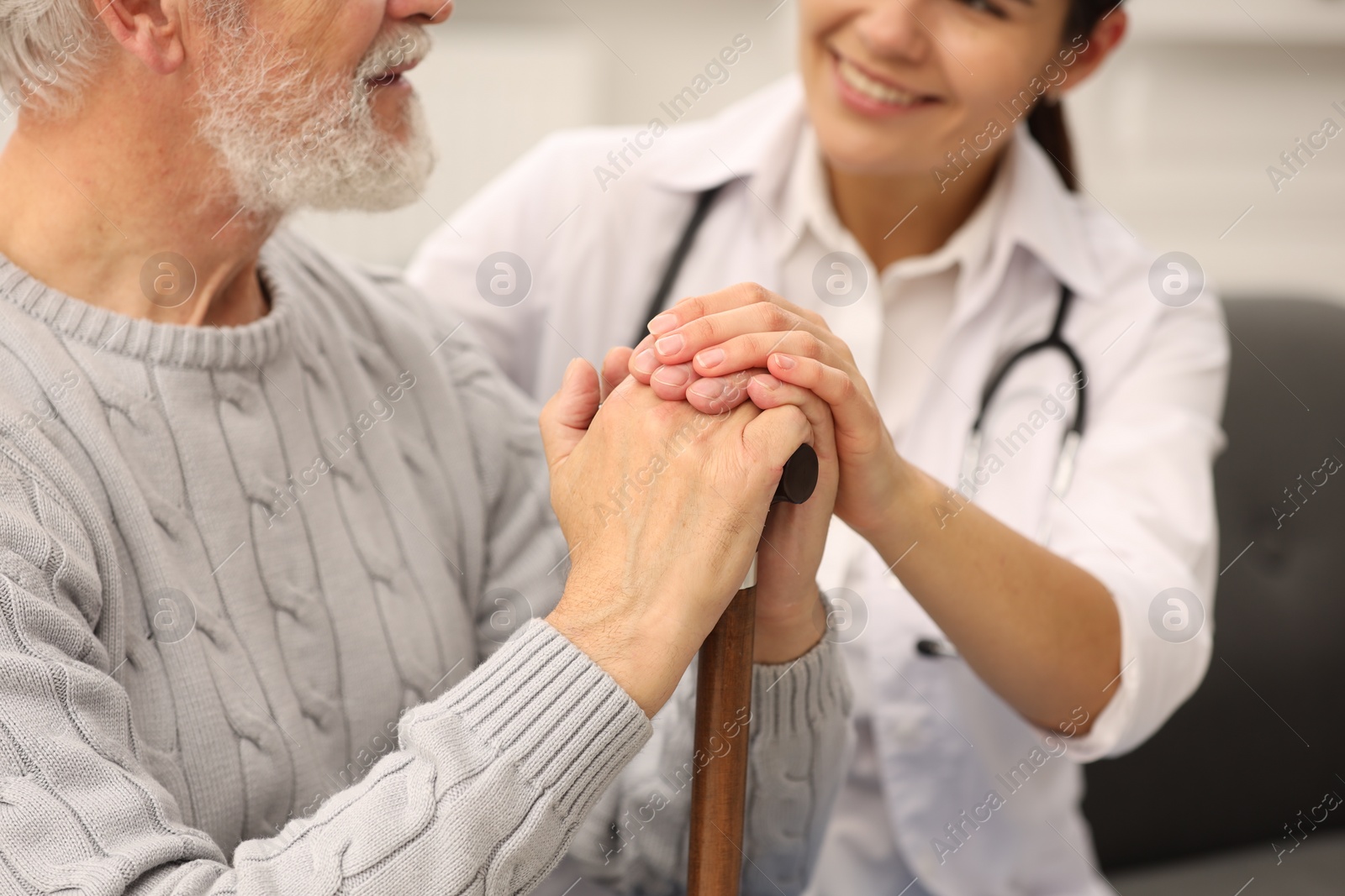 Photo of Smiling nurse supporting elderly patient indoors, closeup