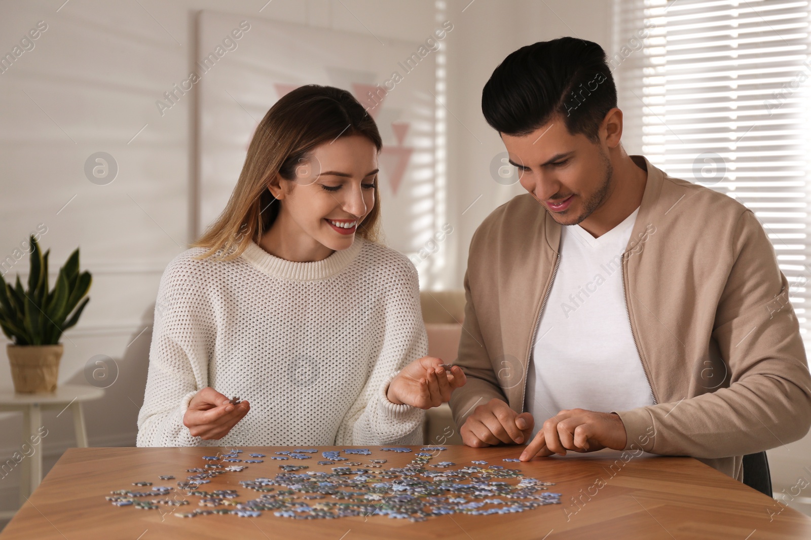 Photo of Happy couple playing with puzzles at home