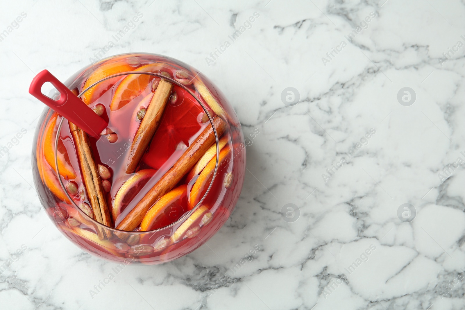 Photo of Glass bowl of aromatic punch drink on white marble table, top view. Space for text