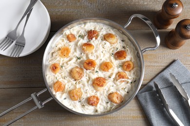 Photo of Delicious scallop pasta served on wooden table, flat lay