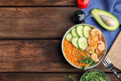 Delicious lentil bowl with shrimps and cucumber on wooden table, flat lay. Space for text