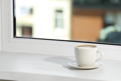 Cup of aromatic coffee on white sill near window indoors, space for text