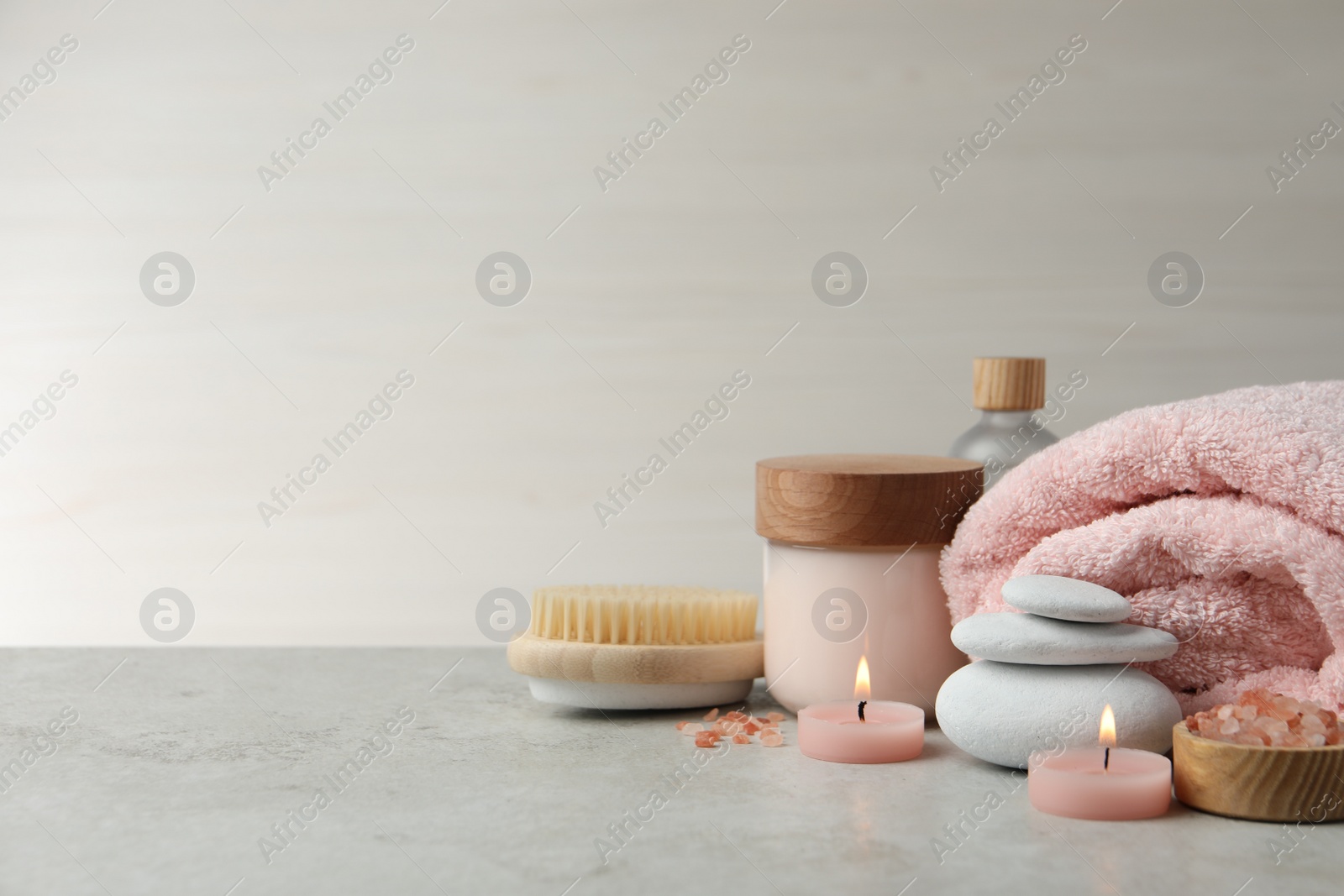 Photo of Beautiful composition with burning candles and different spa products on light grey table. Space for text