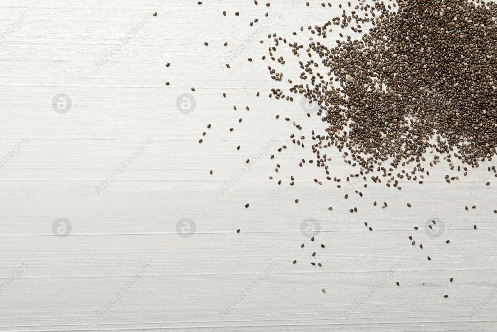 Photo of Chia seeds on white wooden table, flat lay. Space for text