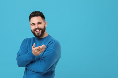 Photo of Portrait of happy young man with mustache on light blue background. Space for text