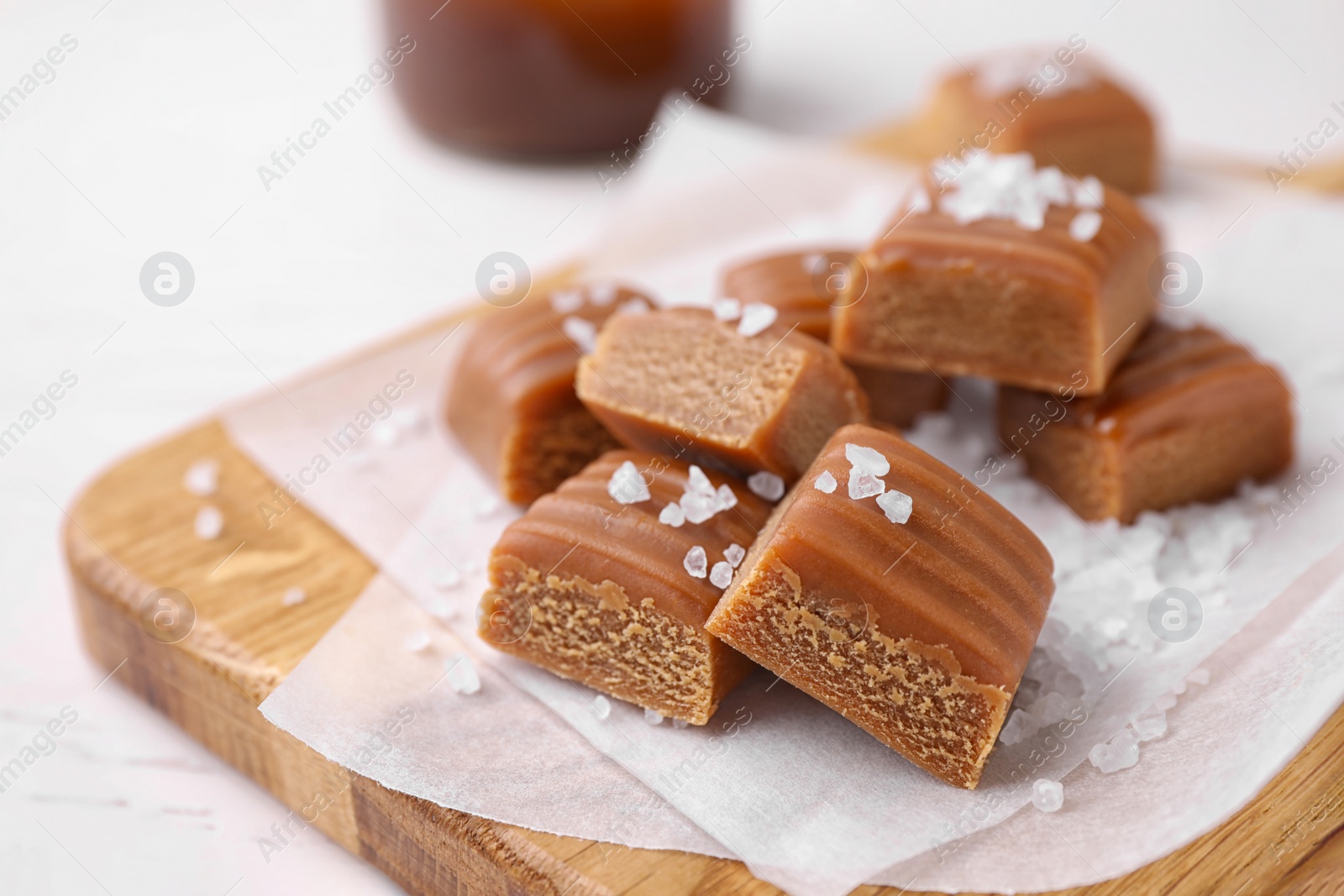 Photo of Delicious salted caramel on wooden board, closeup